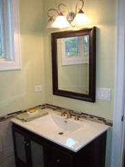 Small bathroom with single vanity and a tile half wall. 