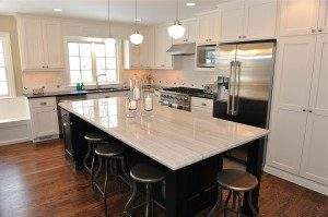 This kitchen uses a different color cabinetry and countertop on the island to contrast the perimeter design and create a focal point for the kitchen. Metallic stools accent the stainless appliances elsewhere in the kitchen 