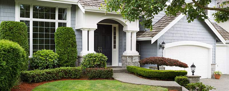 Newly painted exterior of a North American home during summertime with green grass and flower beds