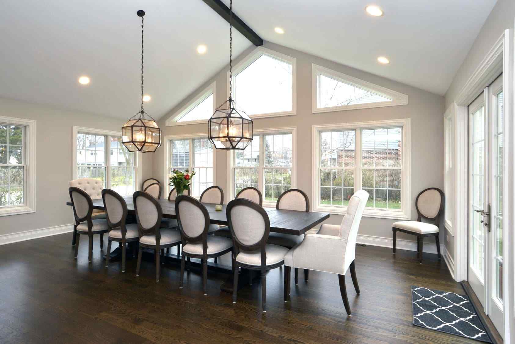 Modern Home Addition Style With Dining Area Below Two Glass Light Fixtures and White Vaulted Ceilings