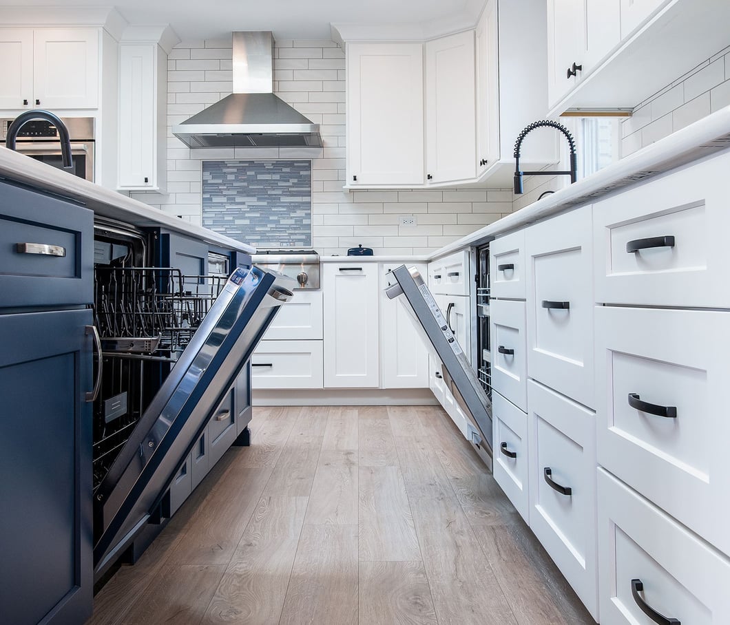 High-capacity kitchen cleanup zone featuring double dishwashers, wide walkways, and custom white shaker cabinetry.