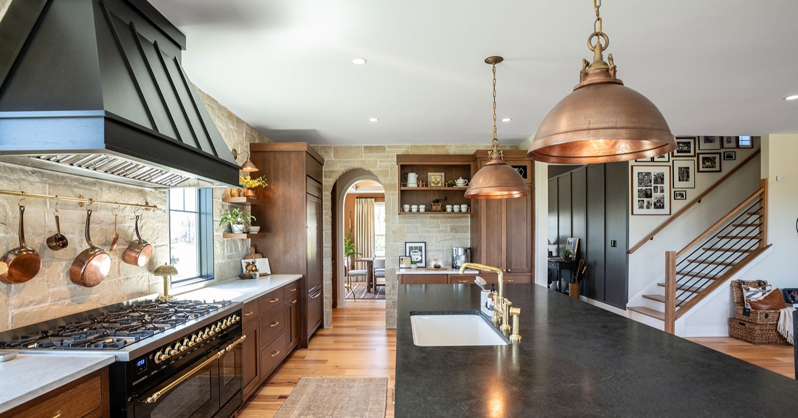 Custom kitchen remodel showing an open-concept layout with work island, prep sink, stone cooktop surround, and natural lighting.
