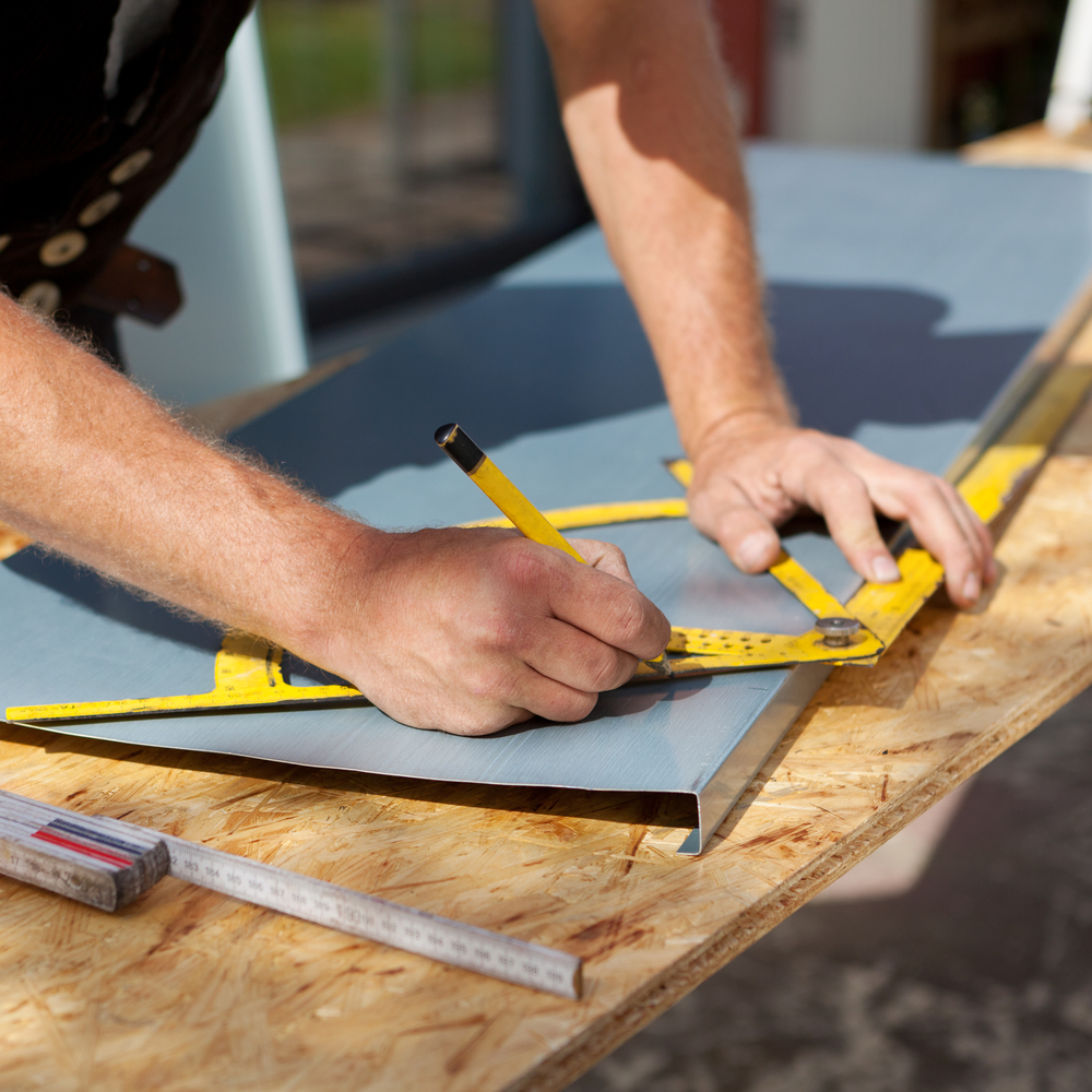 Roofer working with a protractor to make markings on a metal sheet-1