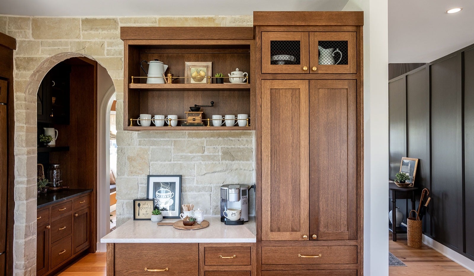 Custom kitchen cabinet remodeling featuring natural wood uppers, dark accent cabinetry, and stone tile backsplash.